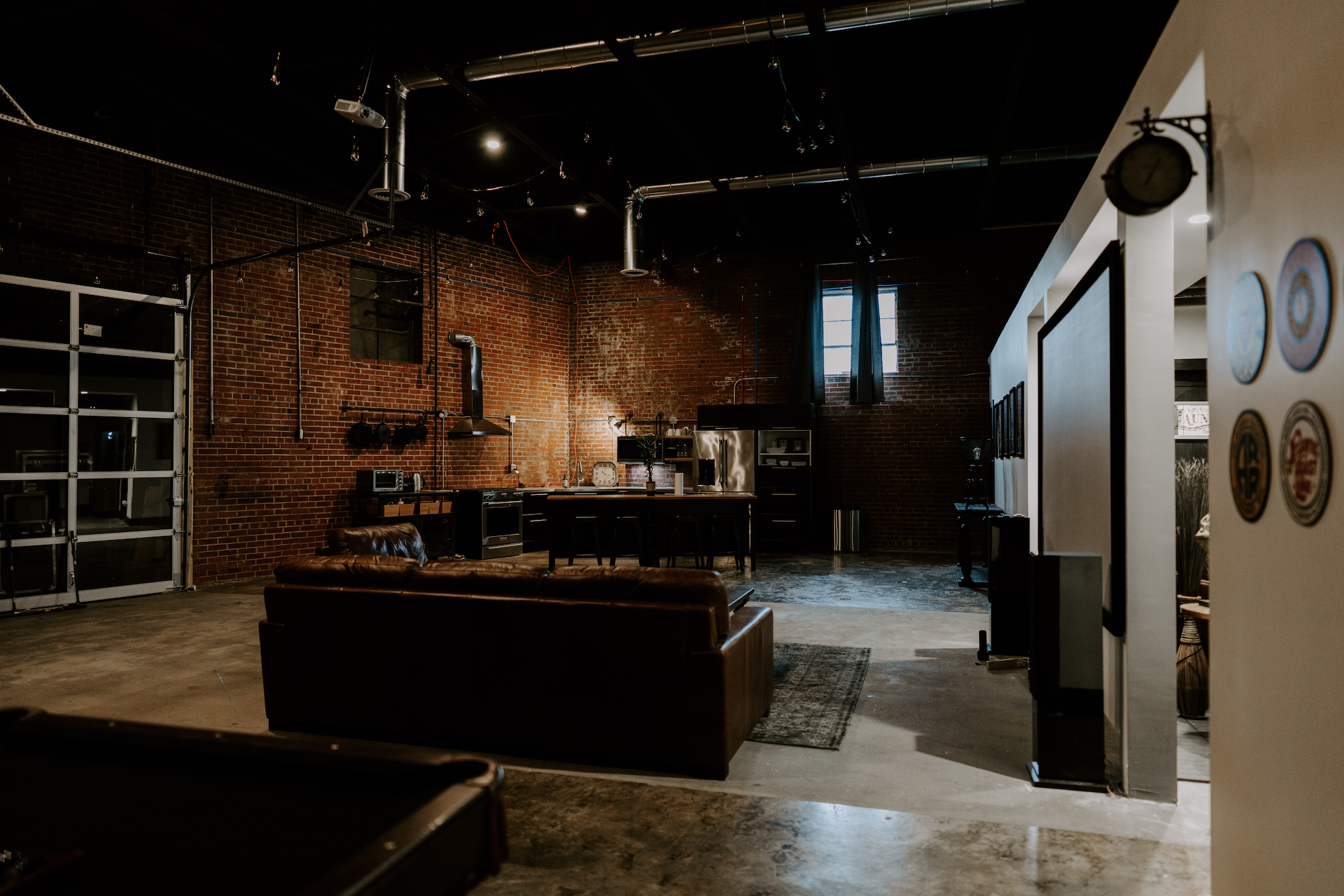 The Loft — brick walls, leather couch, and open kitchen